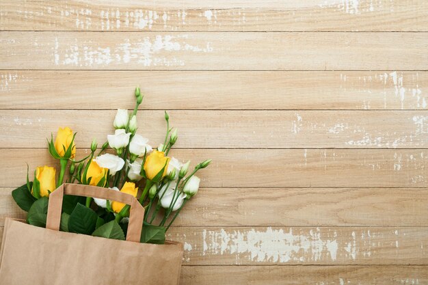 Concept de Pâques Bouquet de roses blanches et jaunes fraîches dans un sac en papier sur fond en bois ancien Concept de célébration de la Pâque Pesah