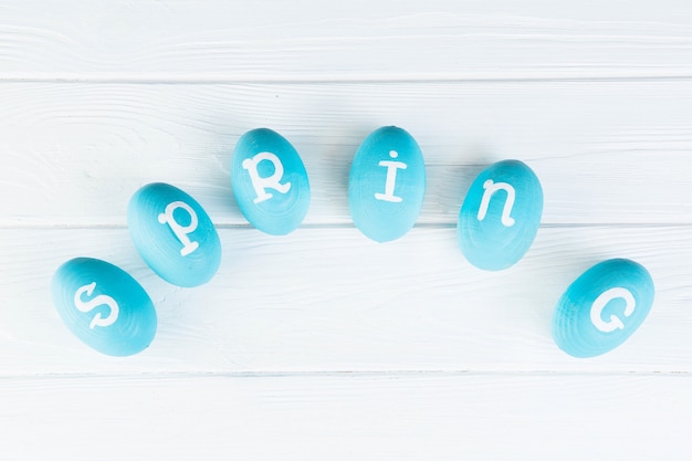 Concept de Pâques. Oeufs bleus avec inscription "printemps" sur table en bois blanc.