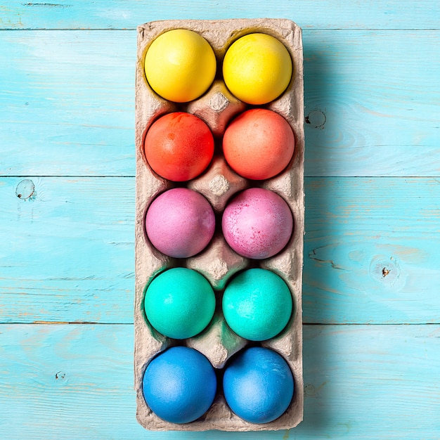 Concept de Pâques. Oeufs colorés dans des emballages en carton sur fond de bois bleu. Vue de haut en bas ou à plat. Carré