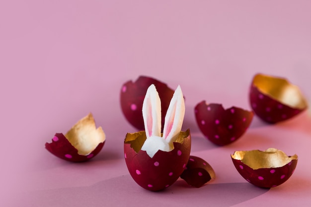 Concept de Pâques. Oeufs colorés sur fond rose, lapin de Pâques se cachant