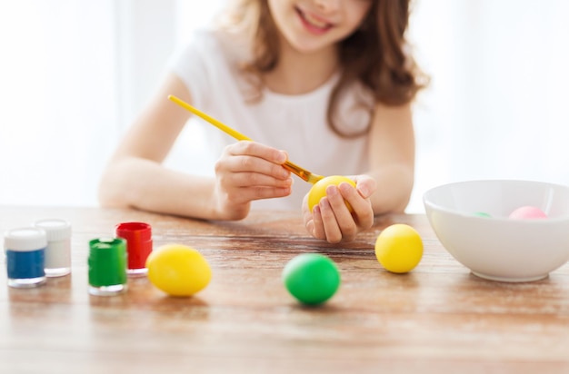 concept de pâques, de vacances et d'enfant - gros plan d'oeufs de coloration de fille pour pâques