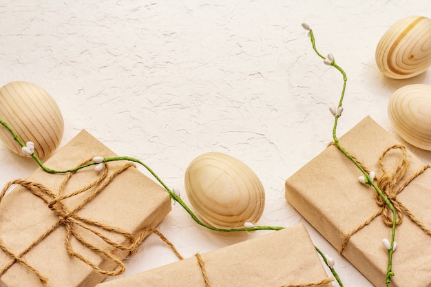 Concept de Pâques zéro déchet. Oeufs en bois, cadeaux en papier kraft. Pas en plastique, tendance écologique. Fond de mastic blanc