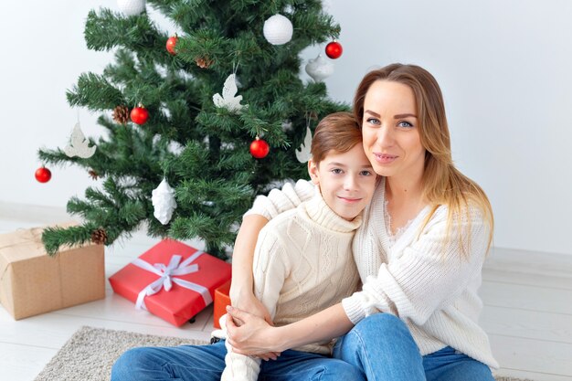 Concept de parent seul et de vacances - Portrait de la mère et de l'enfant célébrant Noël à la maison la veille de Noël