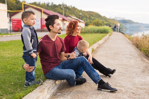 Concept de parentalité, d'enfance et de nature - Famille assise sur le sol vert et regardant petit bateau.