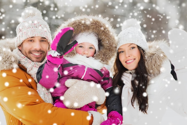 concept de parentalité, de mode, de geste, de saison et de personnes - famille heureuse avec enfant en vêtements d'hiver agitant les mains à l'extérieur