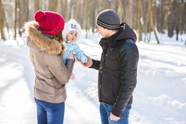 Concept de parentalité, de mode, de saison et de personnes. famille heureuse avec enfant en vêtements d'hiver à l'extérieur.