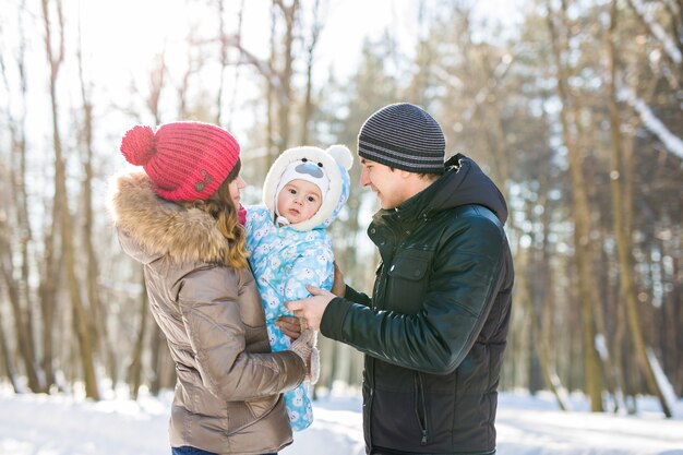 Concept de parentalité, de mode, de saison et de personnes. famille heureuse avec enfant en vêtements d'hiver à l'extérieur.