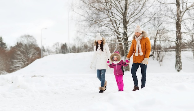 concept de parentalité, de mode, de saison et de personnes - famille heureuse avec enfant en vêtements d'hiver marchant à l'extérieur