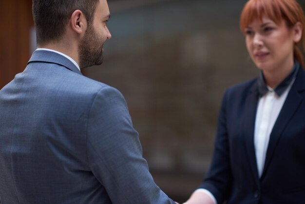 Photo concept de partenariat avec un homme d'affaires et une femme se serrer la main et prendre un accord dans un intérieur de bureau moderne