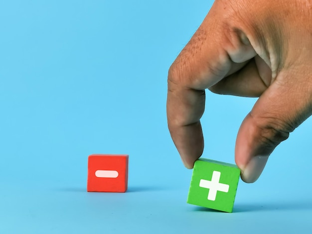 Photo concept de partie positive et négative. choisissez à la main et choisissez le symbole plus sur un cube en bois