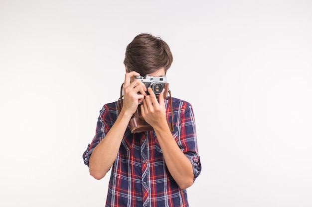 Concept de passe-temps et de loisirs de personnes - jeune homme hipster utilisant son appareil photo vintage sur fond blanc.