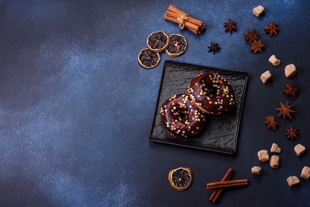 Concept de pâtisseries Beignets au glaçage au chocolat avec pépites sur une table en béton foncé