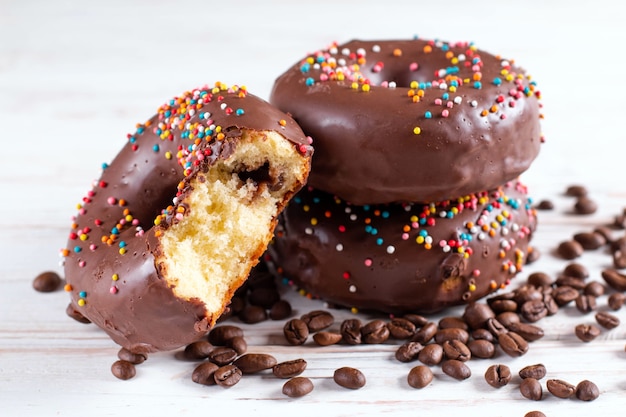 Concept de pâtisseries. Donuts avec glaçage au chocolat sur fond flou de table en bois blanc.