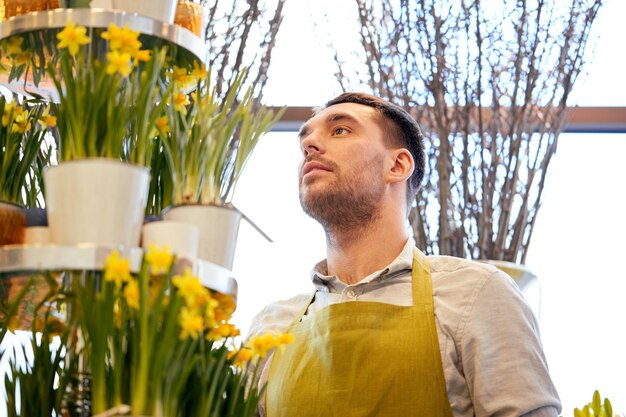 concept de personnes, d'affaires, de vente et de fleuristerie - homme fleuriste avec des fleurs de narcisse au fleuriste