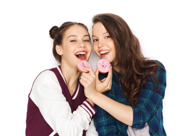 concept de personnes, d'amis, d'adolescents et d'amitié - jolies adolescentes souriantes et heureuses avec des beignets mangeant et s'amusant