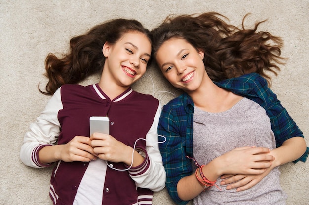 concept de personnes, d'amis, d'adolescents et de technologie - jolie adolescente souriante et heureuse avec des smartphones et des écouteurs écoutant de la musique