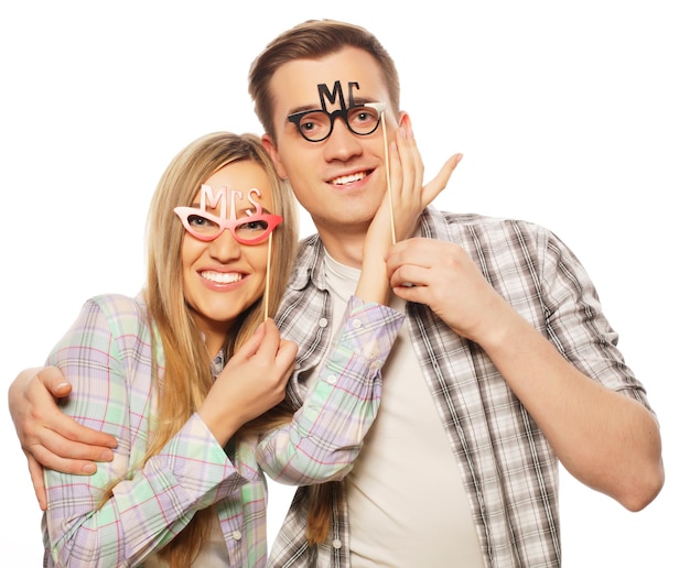 Concept de personnes, d'amitié, d'amour et de loisirs - joli couple tenant des lunettes de fête sur un bâton