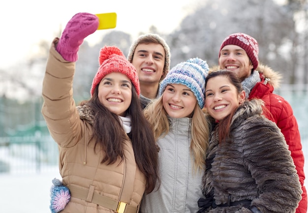 concept de personnes, d'amitié, de technologie, d'hiver et de loisirs - amis heureux prenant un selfie avec un smartphone à l'extérieur