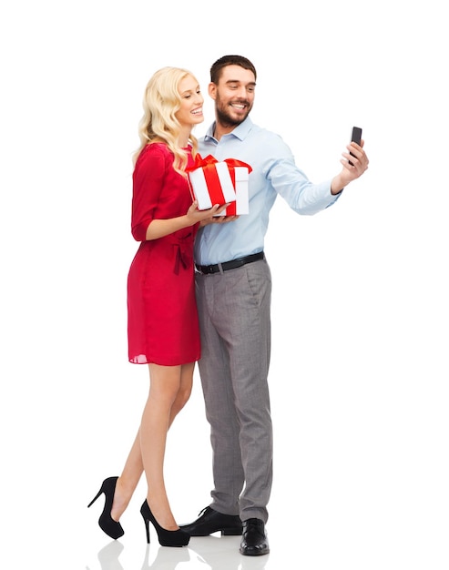 concept de personnes, d'amour, de couple, de technologie et de vacances - heureuse jeune femme et homme avec des cadeaux d'anniversaire prenant selfie par smartphone