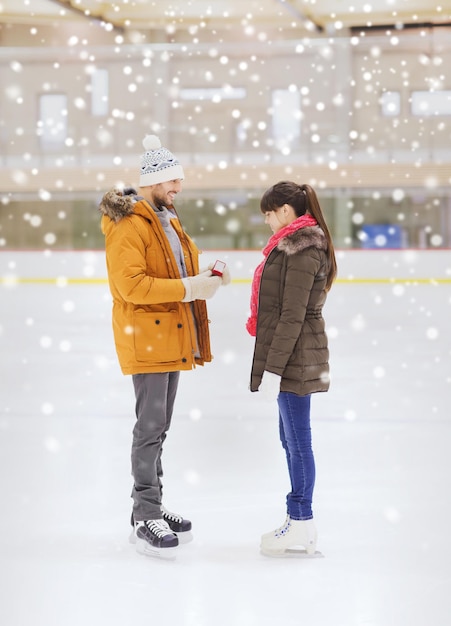 concept de personnes, d'amour, de proposition, de sport et de loisirs - couple heureux avec bague de fiançailles sur patinoire