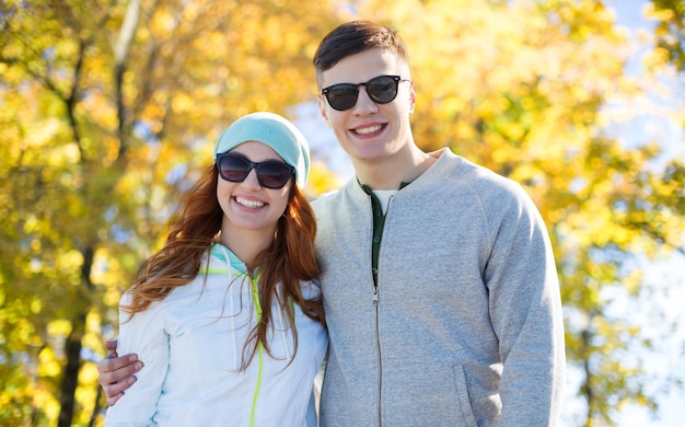 concept de personnes, d'amour, de saison et d'amitié - heureux couple d'adolescents marchant sur fond de parc d'automne