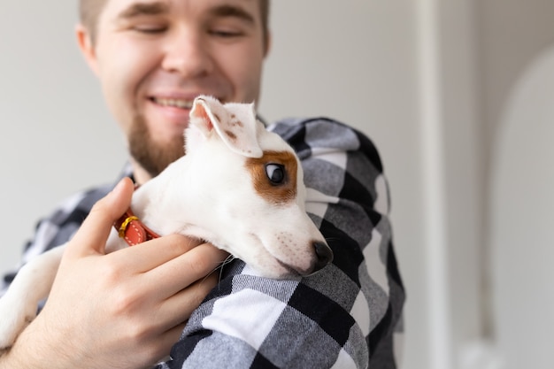 Concept de personnes, d'animaux et d'animaux - gros plan sur un jeune homme tenant un chiot jack russell terrier.