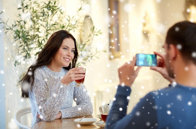 concept de personnes, de communication et de rencontres - homme avec smartphone prenant une photo d'une femme buvant du thé au café ou au restaurant