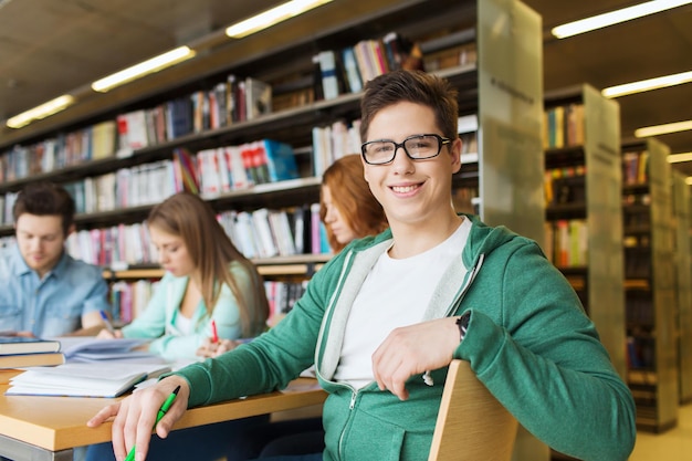 concept de personnes, de connaissances, d'éducation et d'école - garçon étudiant heureux lisant des livres à la bibliothèque