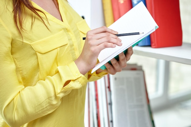 Photo concept de personnes, d'éducation et d'entreprise - gros plan de mains féminines avec carnet et crayon au bureau ou à l'école