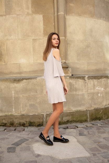 Concept de personnes, d'émotions, de naturel, de beauté et de mode de vie - jeune belle femme joyeuse marchant sur la vieille rue de la ville tropicale. Jolie fille vous regarde et souriant