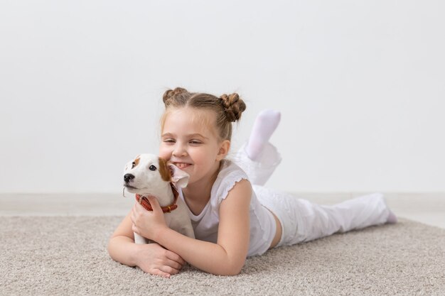 Concept De Personnes, D'enfants Et D'animaux Domestiques - Petite Fille Allongée Sur Le Sol Avec Un Mignon Chiot Jack Russell Terrier