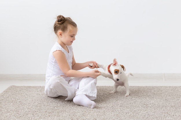 Concept de personnes, d'enfants et d'animaux domestiques - petite fille assise sur le sol avec un chiot mignon Jack Russell Terrier