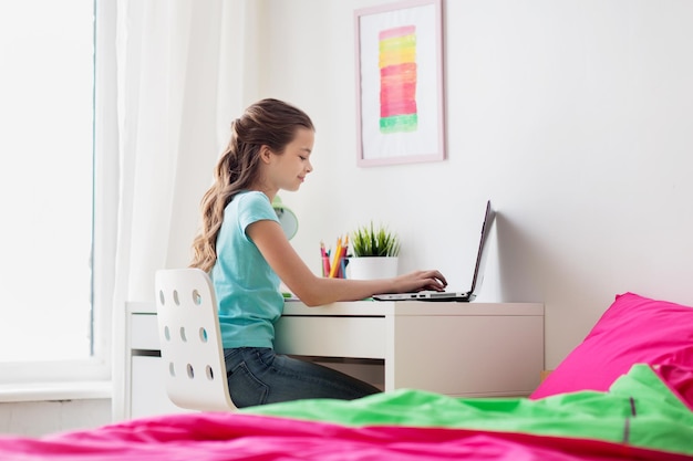 concept de personnes, d'enfants et de technologie - fille tapant sur un ordinateur portable à la maison