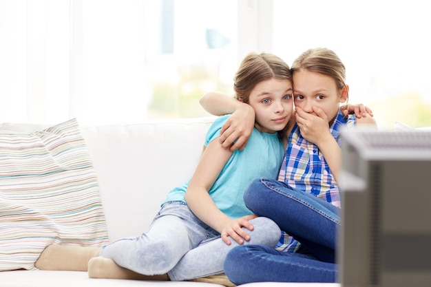 concept de personnes, d'enfants, de télévision, d'amis et d'amitié - deux petites filles effrayées regardant l'horreur à la télévision à la maison