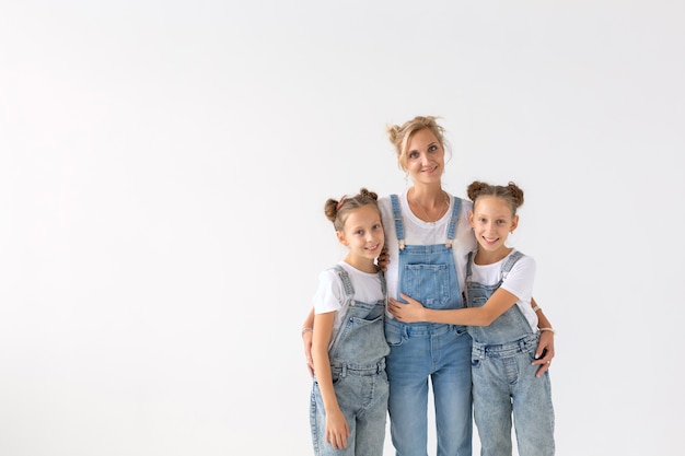 Concept de personnes, de famille et d'enfants - soeurs jumelles avec leur maman sur un mur blanc avec espace de copie.