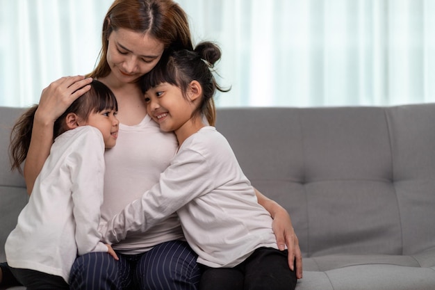 Concept de personnes et de famille - fille souriante heureuse avec la mère étreignant sur le canapé à la maison