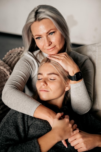 Concept de personnes et de famille fille souriante heureuse avec mère étreignant sur le canapé à la maison