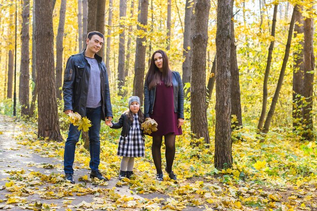 Concept de personnes, de famille et de loisirs - famille heureuse avec fille marchant dans le parc en automne.