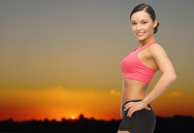 concept de personnes, de fitness et de sport - femme asiatique heureuse posant à l'extérieur sur fond d'horizon coucher de soleil