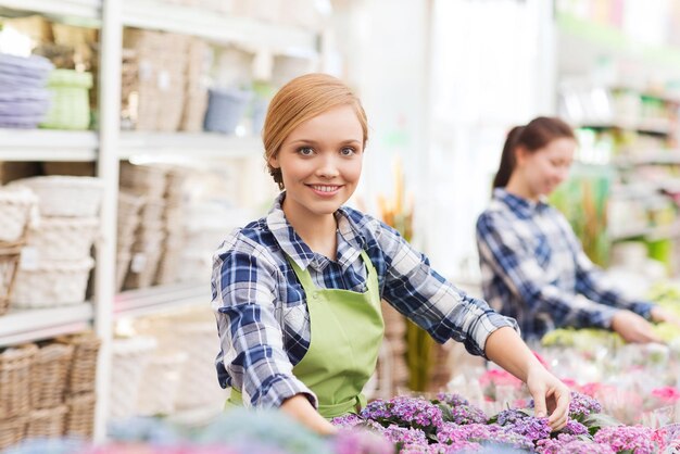 concept de personnes, de jardinage et de profession - femme heureuse ou jardinier prenant soin des fleurs en serre