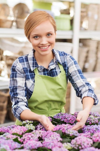 concept de personnes, de jardinage et de profession - femme heureuse ou jardinier prenant soin des fleurs en serre