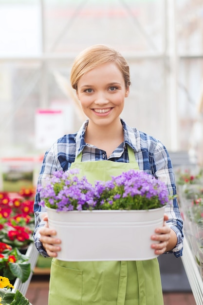 concept de personnes, de jardinage et de profession - femme heureuse ou jardinier tenant des fleurs en serre