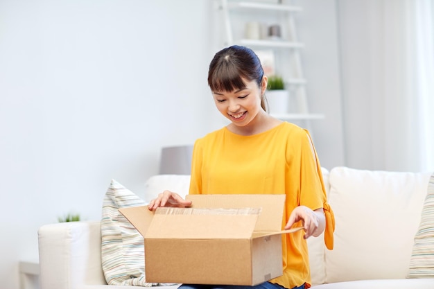 concept de personnes, de livraison, de commerce, d'expédition et d'achat - jeune femme asiatique heureuse avec une boîte à colis en carton à la maison