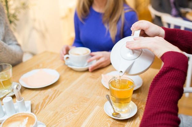 concept de personnes, de loisirs et de boissons - gros plan d'un homme versant du thé d'une marmite à une tasse au café