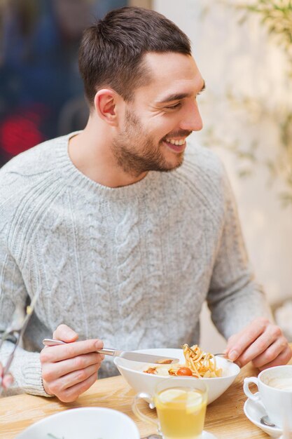 concept de personnes, de loisirs, de restauration et de restauration - jeune homme heureux en train de dîner au restaurant, au café ou à la maison