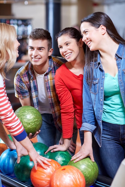 concept de personnes, de loisirs, de sport, d'amitié et de divertissement - amis heureux dans un club de bowling