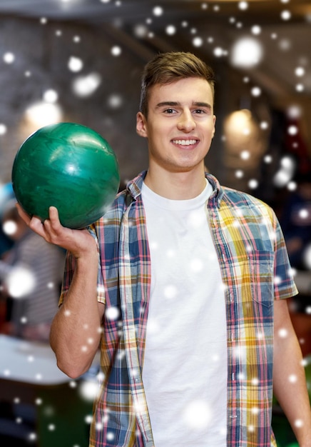 concept de personnes, de loisirs, de sport et de divertissement - jeune homme heureux tenant une balle dans un club de bowling en hiver