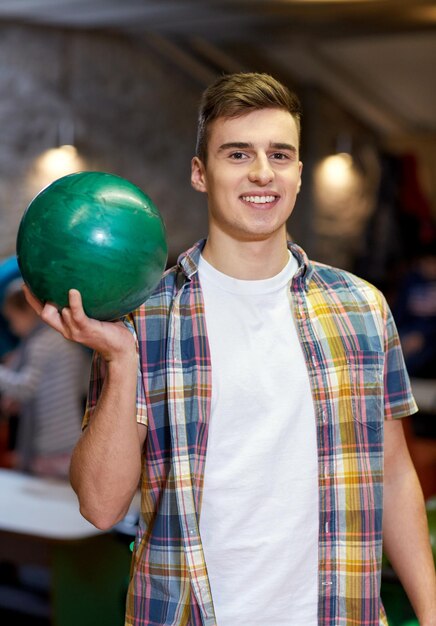 concept de personnes, de loisirs, de sport et de divertissement - jeune homme heureux tenant une balle dans un club de bowling