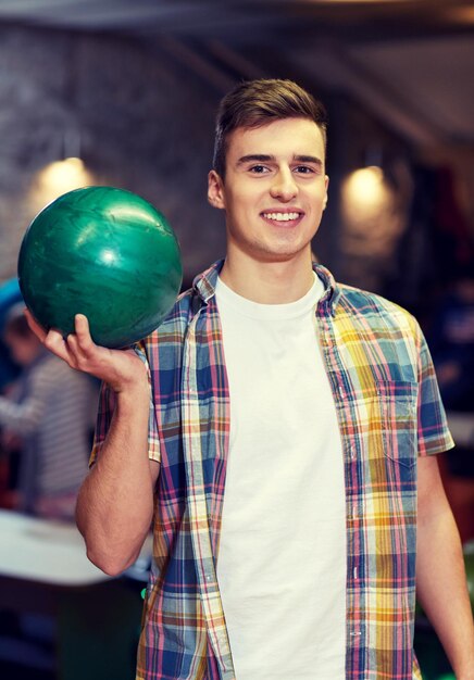 concept de personnes, de loisirs, de sport et de divertissement - jeune homme heureux tenant une balle dans un club de bowling