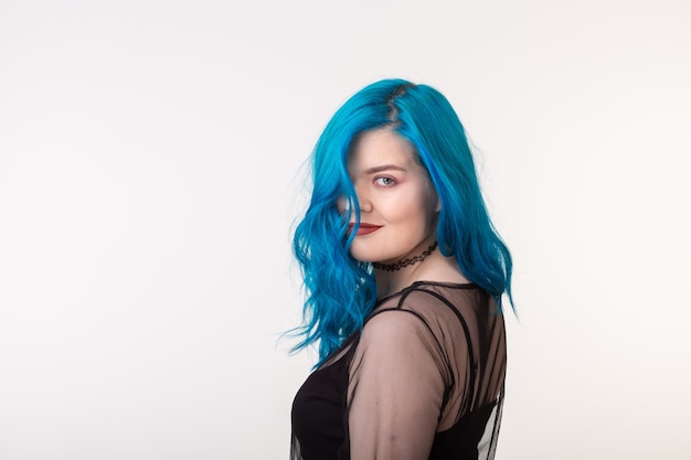 Concept de personnes et de mode belle femme aux cheveux bleus posant sur un mur blanc